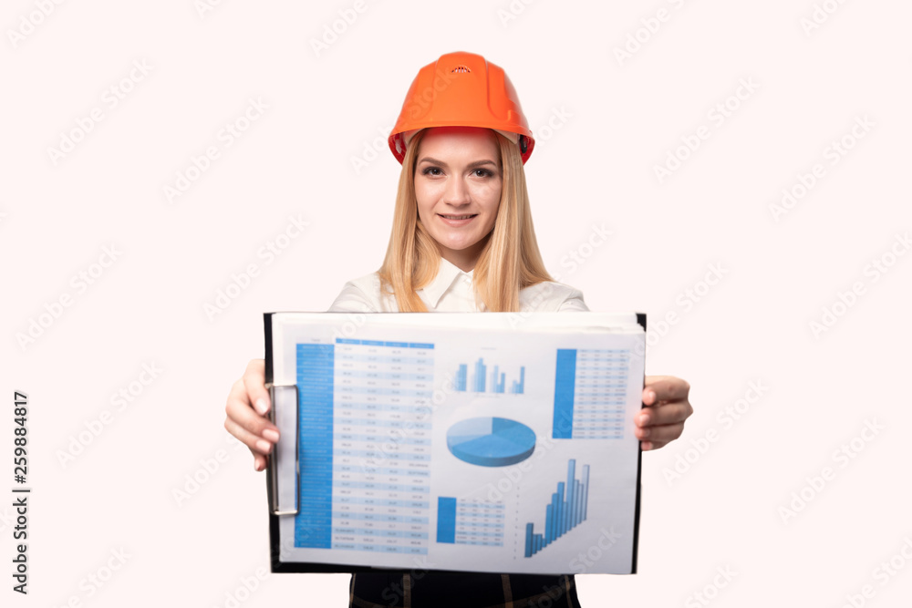 Girl engineer in a protective helmet shows graphics Girl engineer in a protective helmet shows graphics