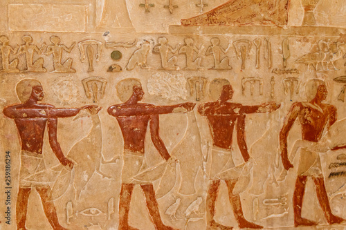 Ancient egyptian paintings and hieroglyphs carved on the stone wall