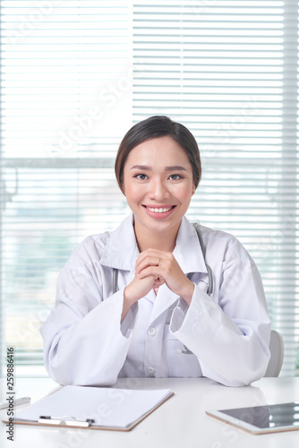 Female doctor working at office desk and smiling at camera