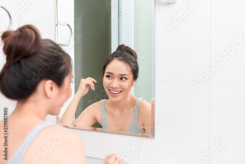 woman applying face cream after daily shower. Making everyday morning routine in bathroom.