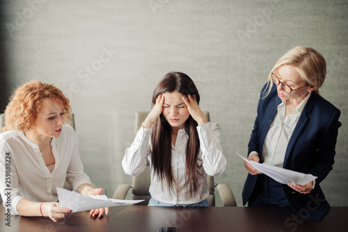 Foto Young female office manager unable to cope with too many tasks from her boss and supervisor, suffering stress, pressing her head with desperate expression