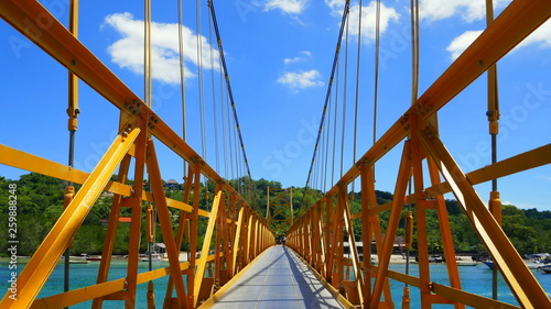 zentraler Blick auf gelbe Brücke zwischen den Inseln Lembongan und Ceningan in Indonesien unter blauem Himmel © globetrotter1