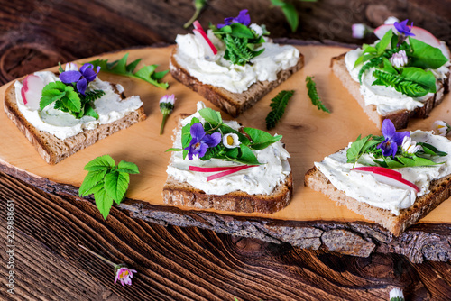 Delicious sandwiches with spread of fresh wild meadow herbs, beautifully decorated with fresh radishes served on a rustic wooden board photo