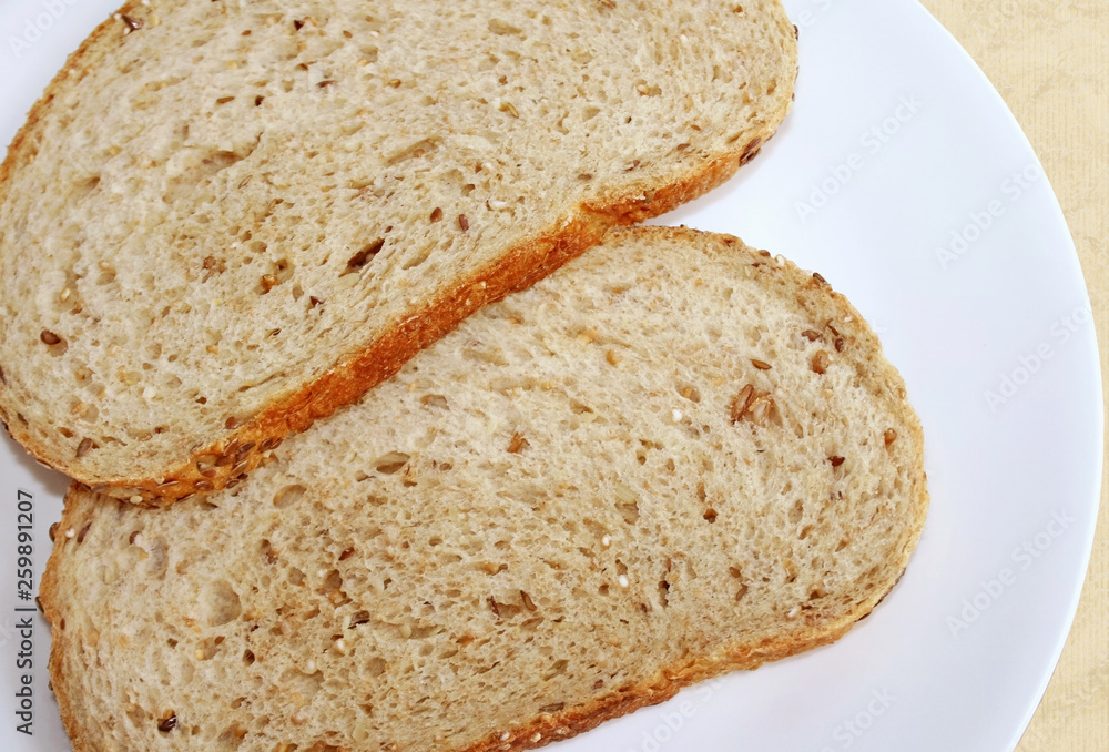 Two slices of whole grain bread on a white plate Two slices of whole grain bread on a white plate