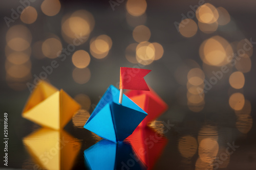 Blue paper ship with flag among other ships. Leadership concept.