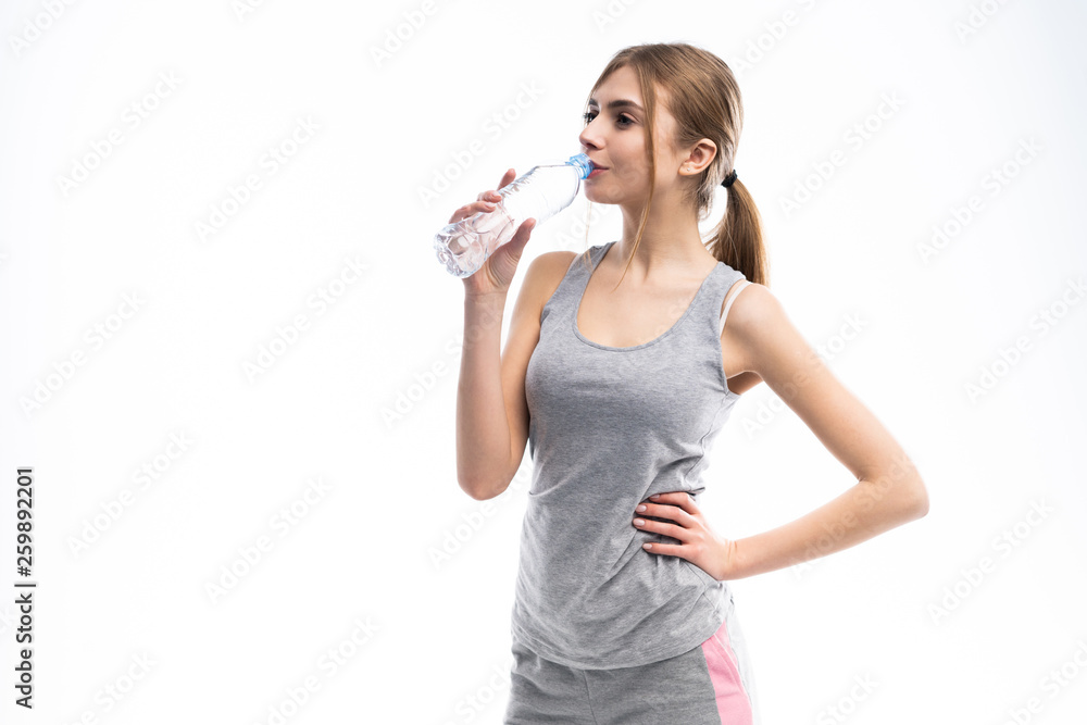 Female fitness model holding a water bottle in a white studio environment. Female fitness model holding a water bottle in a white studio environment.