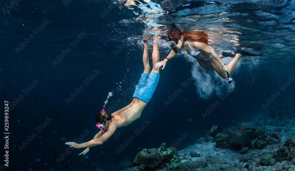 Young couple snorkeling and do skin diving over the coral reef edge in the tropical sea in the Maldives
