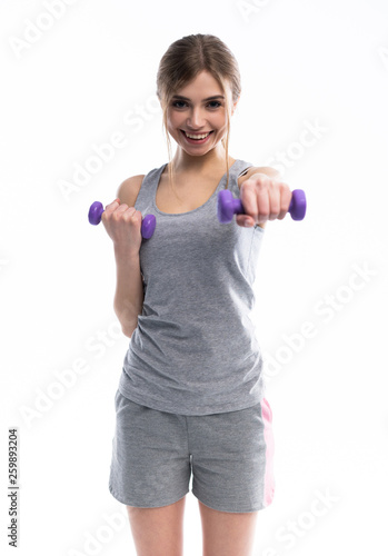 Portrait of pretty sporty girl holding weights dumbbells and make exercises on white background.