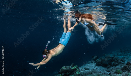 Young couple snorkeling and do skin diving over the coral reef edge in the tropical sea in the Maldives