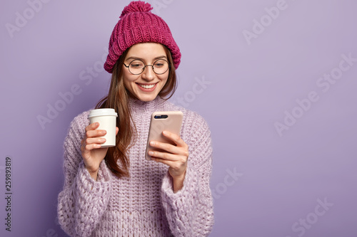 Satisfied young woman reads interesting invitation message, looks at display ...