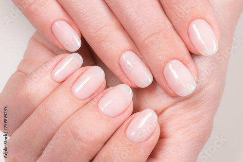 Closeup top view of elegant pastel pink natural manicure. Female hands isolated on white background. Horizontal color photography. photo