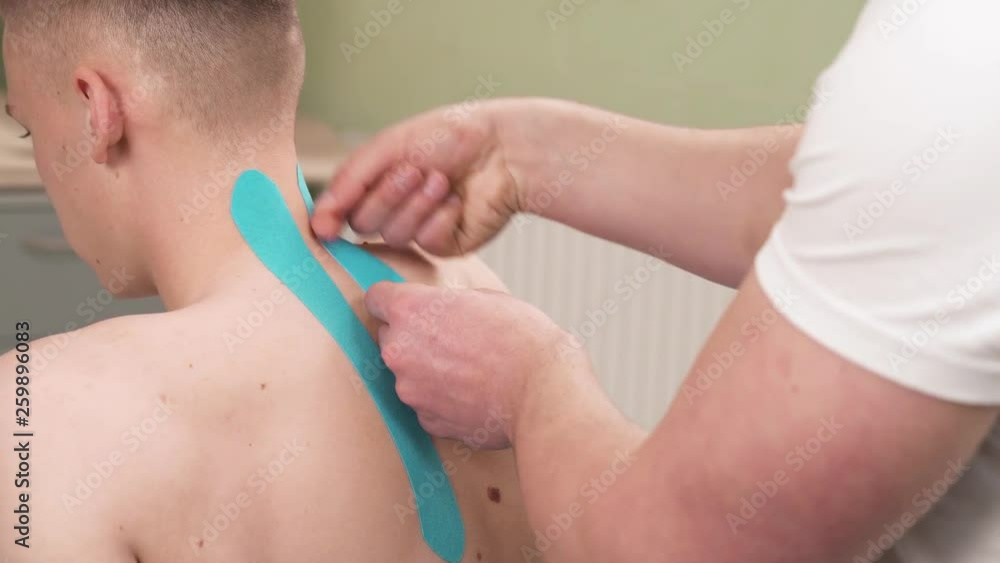 A close-up demonstration video of a professional therapist fixing stretchy kinesiology tape on patients neck. Physiotherapy and rehabilitation, kinesio therapy, treatment A close-up demonstration video of a professional therapist fixing stretchy kinesiology tape on patients neck. Physiotherapy and rehabilitation, kinesio therapy, treatment