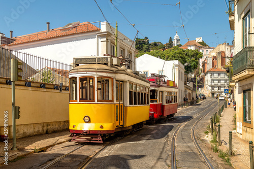 Yellow and red vintage trams on old streets of Lisbon, Alfama, Portugal, popular touristic attraction and destination.