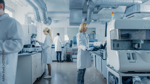 Team of Research Scientists Working On Computer, with Medical Equipment, Analyzing Blood and Genetic Material Samples with Special Machines in the Modern Laboratory. photo