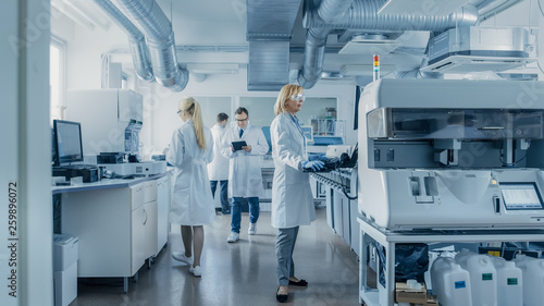Team of Research Scientists Working On Computer, with Medical Equipment, Analyzing Blood and Genetic Material Samples with Special Machines in the Modern Laboratory. photo
