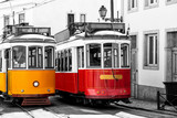 Yellow and red vintage trams on old streets of Lisbon, Alfama, Portugal, popular touristic attraction and destination. Black and white picture with a coloured tram.