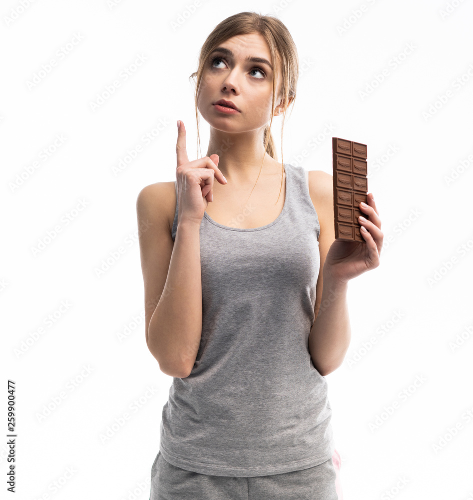 Young woman unhappy with her weight holding chocolate, isolated on white. Young woman unhappy with her weight holding chocolate, isolated on white.