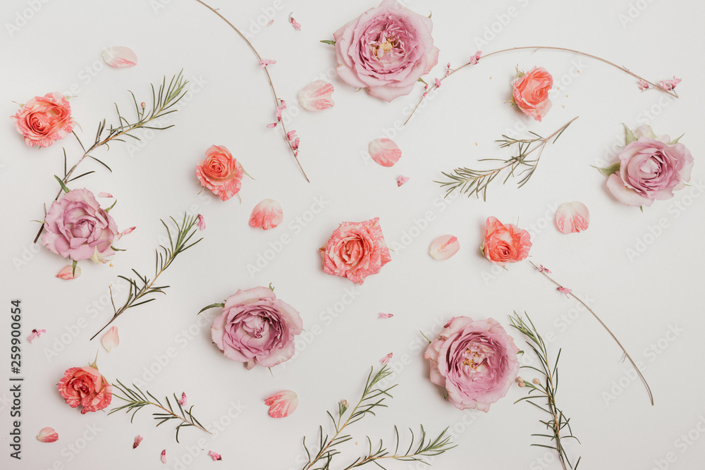Fototapeta premium Flower composition. Pink roses and green branches on a white background. Pastel photography, flat, top view