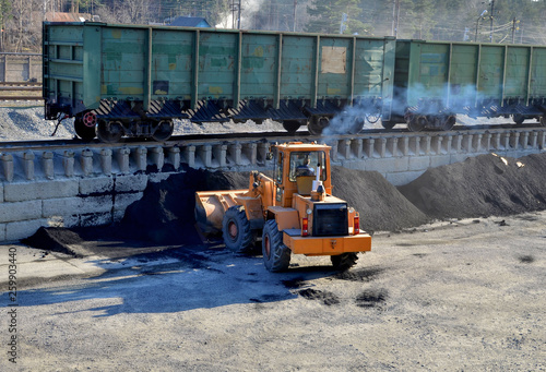 Wheel loader unload coal at a cargo railway station in a mining quarry photo