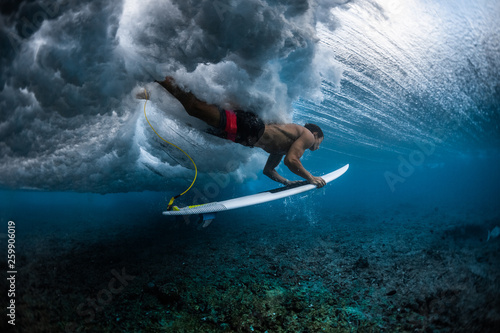 Fototapeta Naklejka Na Ścianę i Meble -  Surfer dives under the breaking wave in the tropics