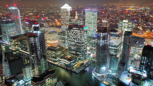 Aerial drone night shot from iconic Canary Wharf illuminated skyscrapers business and financial area, Docklands, Isle of Dogs, London, United Kingdom
