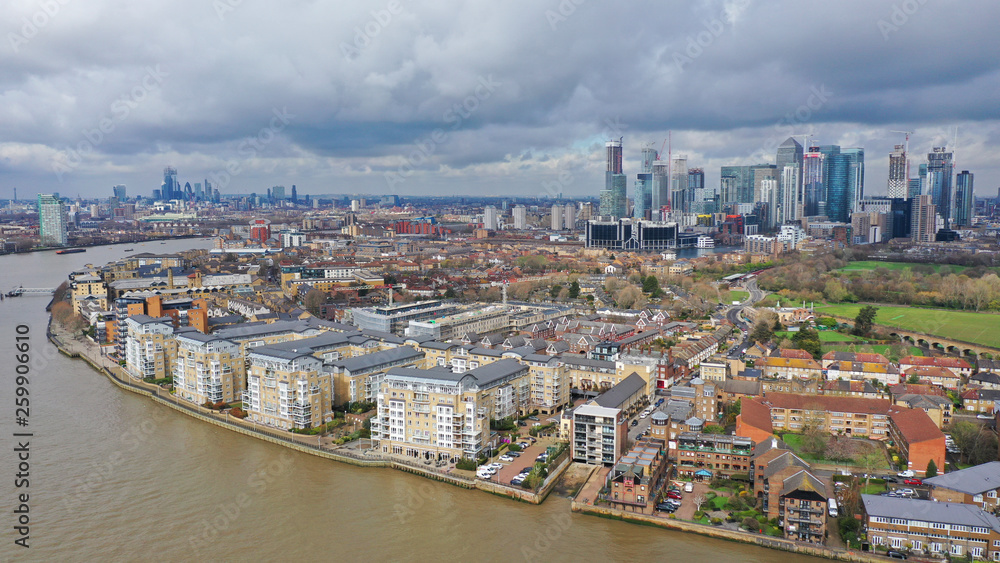 Naklejka premium Aerial drone shot from iconic Canary Wharf skyscraper business and financial area with lots of clouds, Docklands, Isle of Dogs, London, United Kingdom