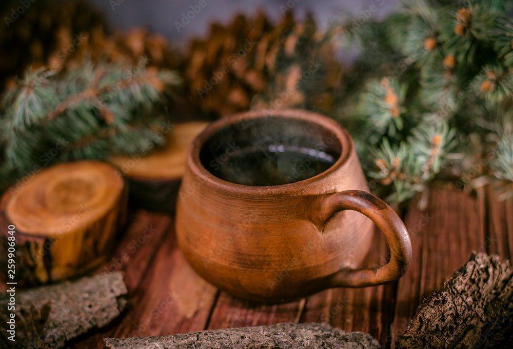 Pot of hot herbal tea, fir cones and paws of blue fir on wooden background Pot of hot herbal tea, fir cones and paws of blue fir on wooden background