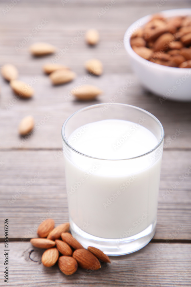 Almond milk in glass with almonds on grey Almond milk in glass with almonds on grey