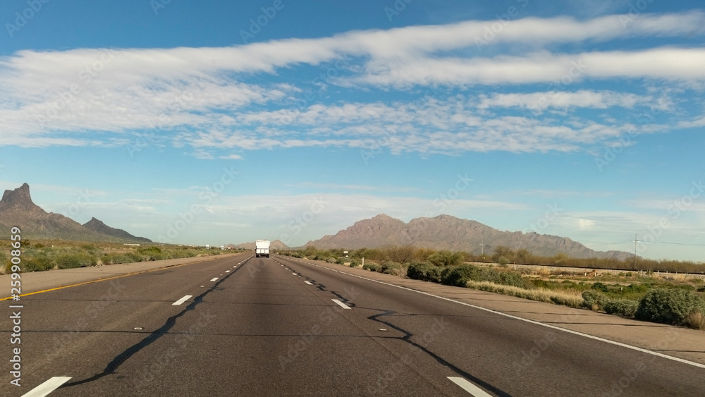Traveling Arizona highway under blue sky.