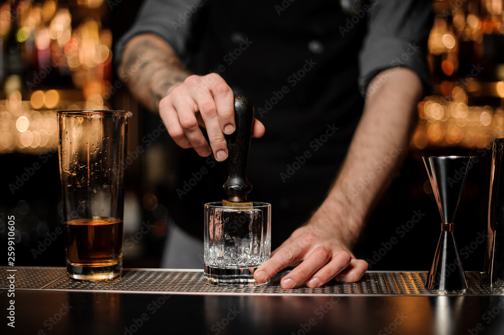 Tattooed bartender makes an imprint on the ice cube in the glass Tattooed bartender makes an imprint on the ice cube in the glass