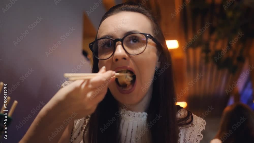 Woman in glasses eats rolls in the pan-Asian restaurant chopsticks. Woman in glasses eats rolls in the pan-Asian restaurant chopsticks.
