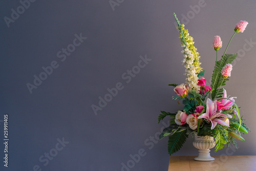 Fake flowers in a vase on wood table with gray background