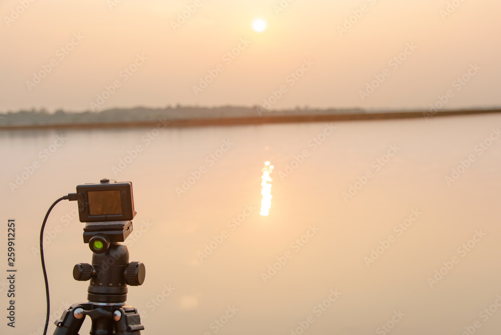 Obraz premium Take pictures sunset at the river with Action camera on tripod