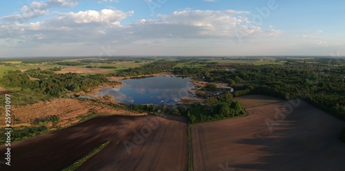 Spring cultivated agriculture fields, groves and lake panorama, aerial