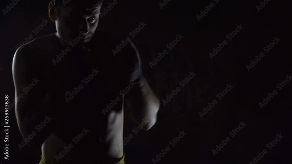 Boxer training in the gym on a dark background Boxer training in the gym on a dark background