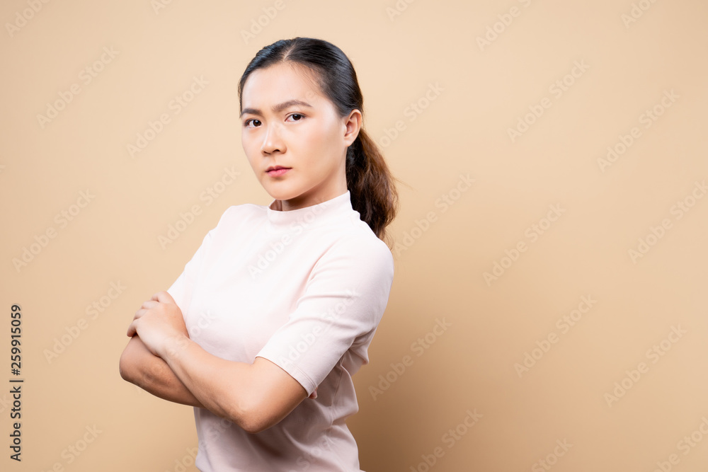 Angry woman standing isolated over beige brown background Angry woman standing isolated over beige brown background