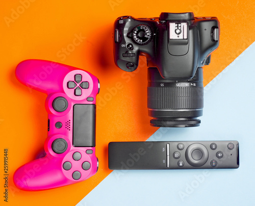 Modern gadgets and devices on a colored paper background. Dslr camera, remote, gamepad. Top view..