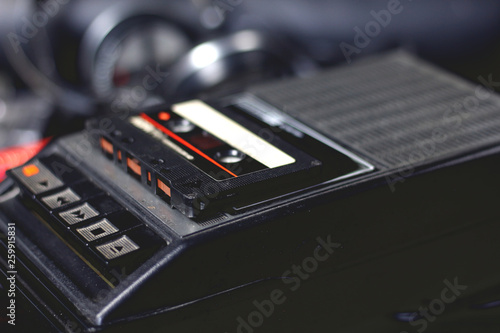 Old retro vintage black portable audio cassette player and recorder with audio tape on top 70s, 80s, 90s style