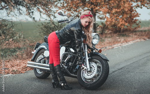 Young beautiful caucasian woman posing with motorcycle on the road. © Alona