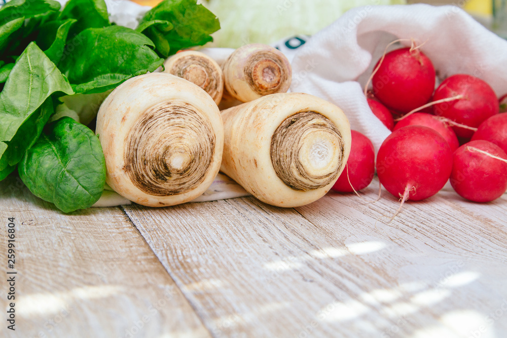 Parsnip, parsley root, radish and spinach in a reusable canvas bags. Closeup grocery photography. Less plastic concept. Local market products Parsnip, parsley root, radish and spinach in a reusable canvas bags. Closeup grocery photography. Less plastic concept. Local market products