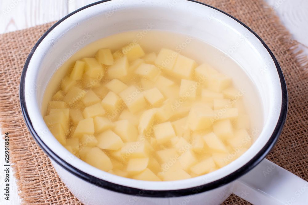 Peeled potatoes in a saucepan on a wooden table Peeled potatoes in a saucepan on a wooden table