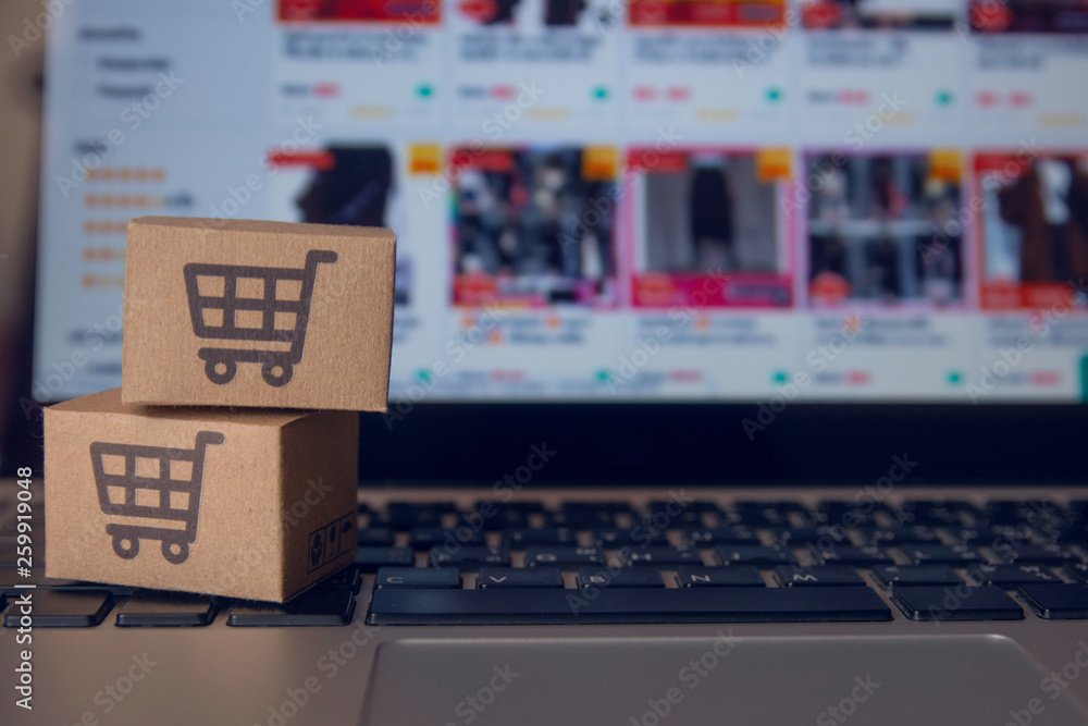 Online shopping : Paper cartons or parcel with a shopping cart logo on a laptop keyboard. Shopping service on The online web and offers home delivery.