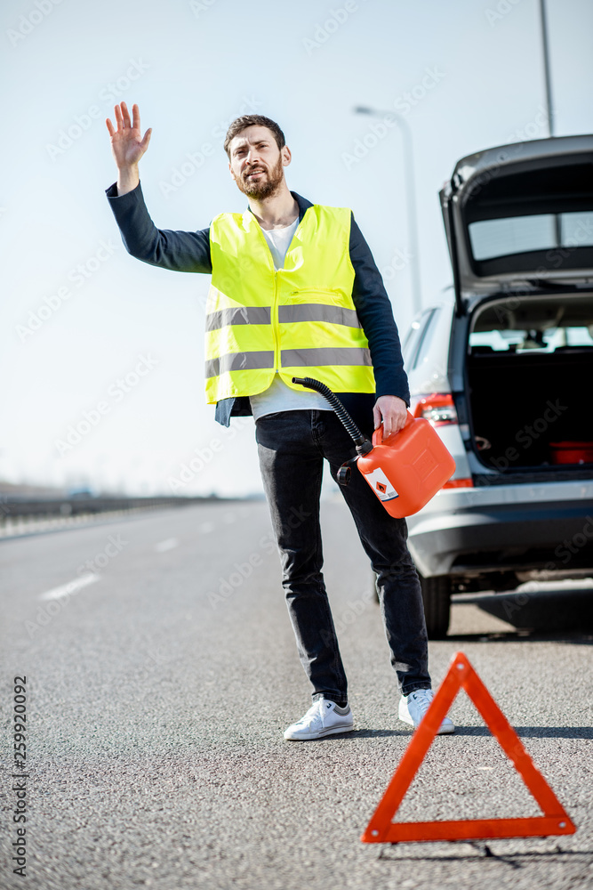 Man stopping car standing with refuel canister on the roadside having no gasoline in his tank