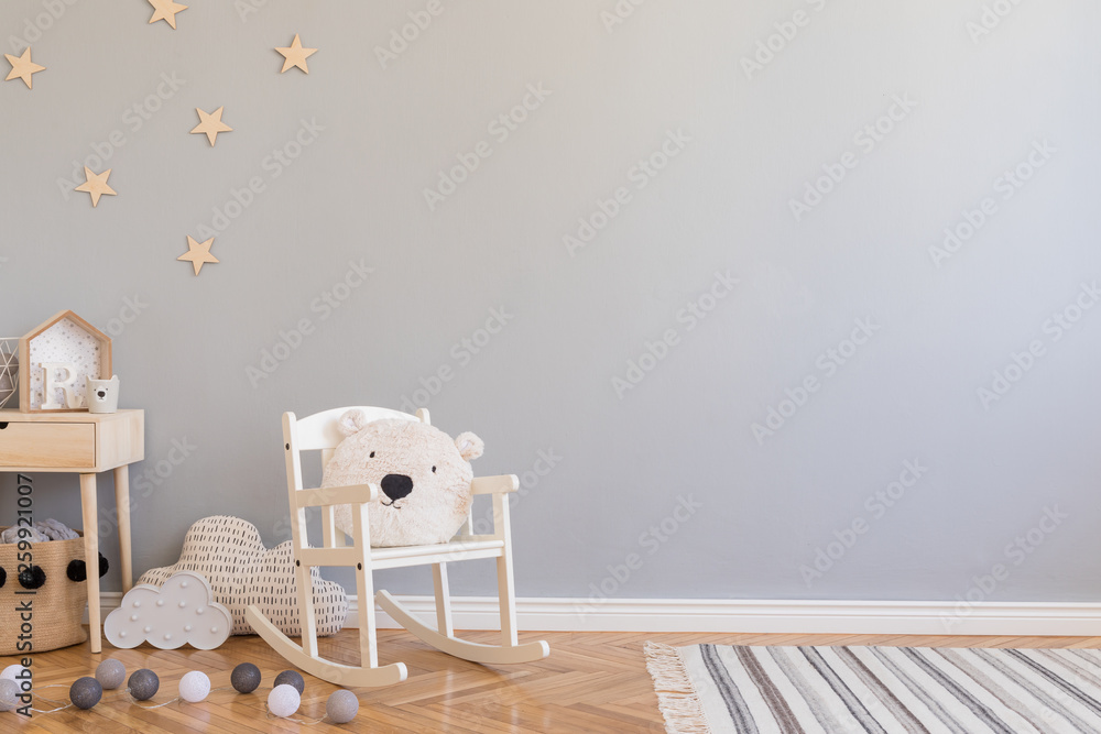 Stylish scandinavian newborn baby room with toys, children's chair, natural basket with teddy bear and small shelf. Modern interior with grey background walls, wooden parquet and stars pattern. - obrazy, fototapety, plakaty 