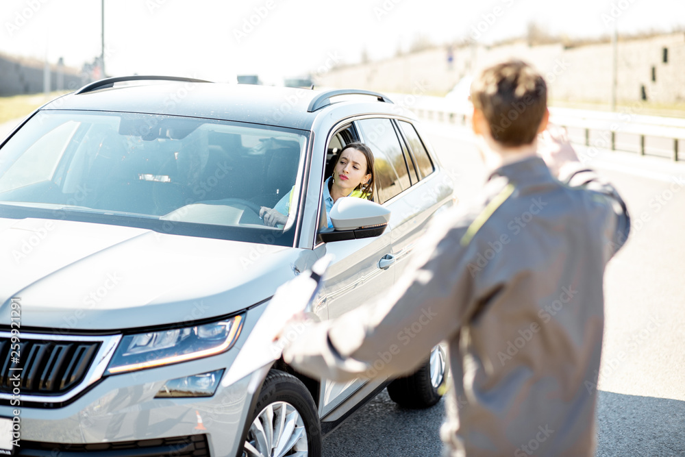 Road assistance worker helping young woman to get out from the roadside after the accident on the highway Road assistance worker helping young woman to get out from the roadside after the accident on the highway