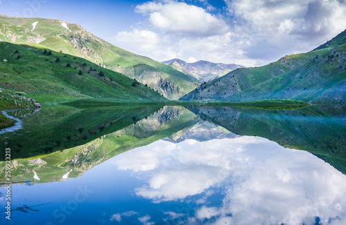 Mountain lake Susyngen  Kazakhstan. Reflection of clouds  green coasts and the blue sky in a surface of the water. 