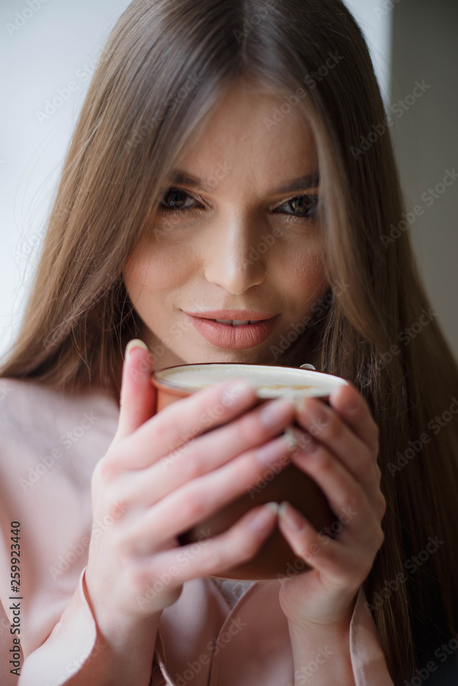 Beautiful girl is drinking coffee and smiling while sitting at the cafe Beautiful girl is drinking coffee and smiling while sitting at the cafe