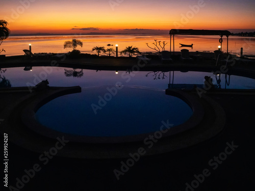 Sunset with a boat and palm trees reflected in the pool