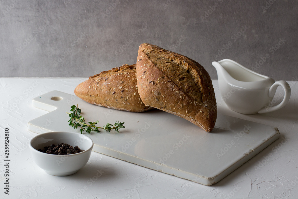 Two loafs of whole grain gluten free homemade bread on white rustic ceramic cutting board. Healthy home food concept Two loafs of whole grain gluten free homemade bread on white rustic ceramic cutting board. Healthy home food concept