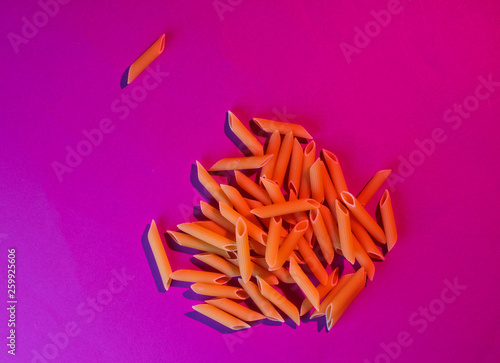 Penne rigata pasta in pink neon light. Top view photo